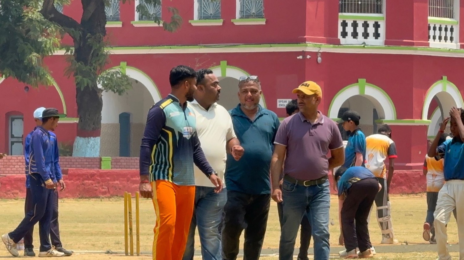 A coach in conversation with match officials at the boundary
